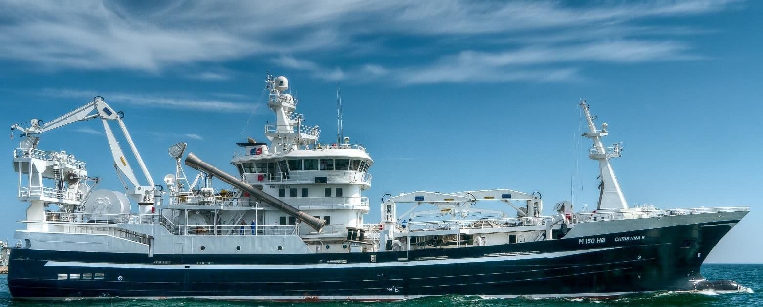 A dark-hulled pelagic trawler under way in calm sea